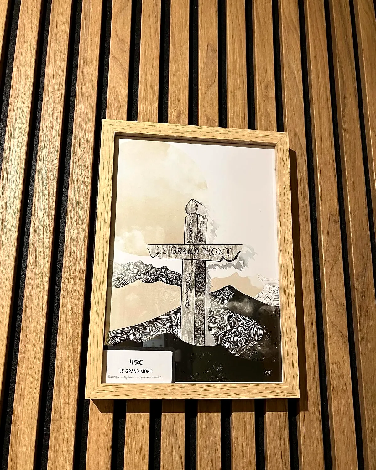 Une illustration de montagne encadrée sur un mur à lattes de bois